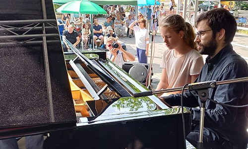 Ein Pianist spielt an einem schwarzen Bechsteinflügel nebst einem Mädchen.