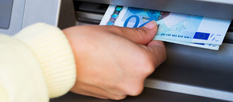 Weibliche Hand entnimmt Euro-Geldscheine aus Geldautomaten