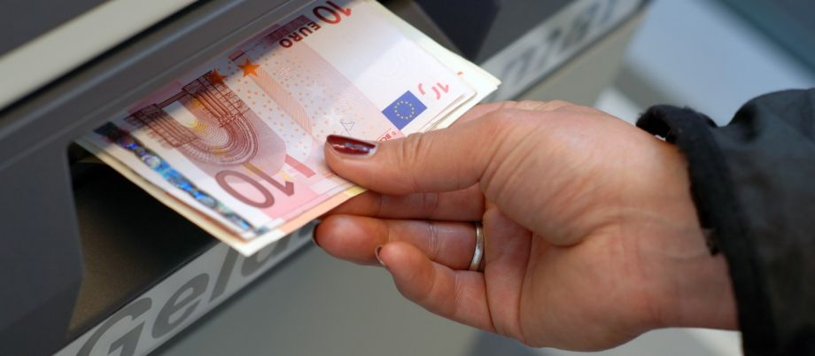 Weibliche Hand entnimmt Euro-Geldscheine aus Geldautomaten