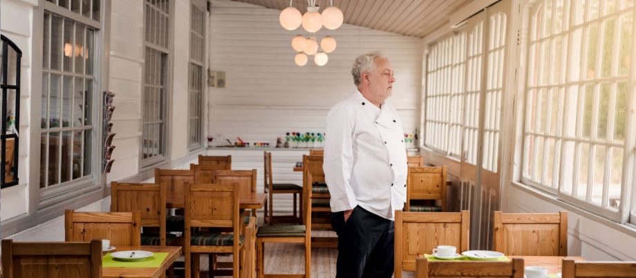 Ein Koch steht in seinem leeren Restaurant und schaut traurig in die Leere